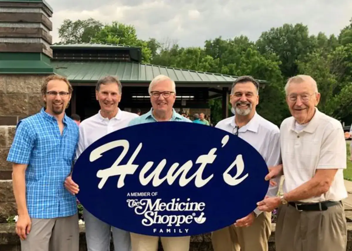 Hunt's team members holding the Hunt's Medicine Shoppe sign